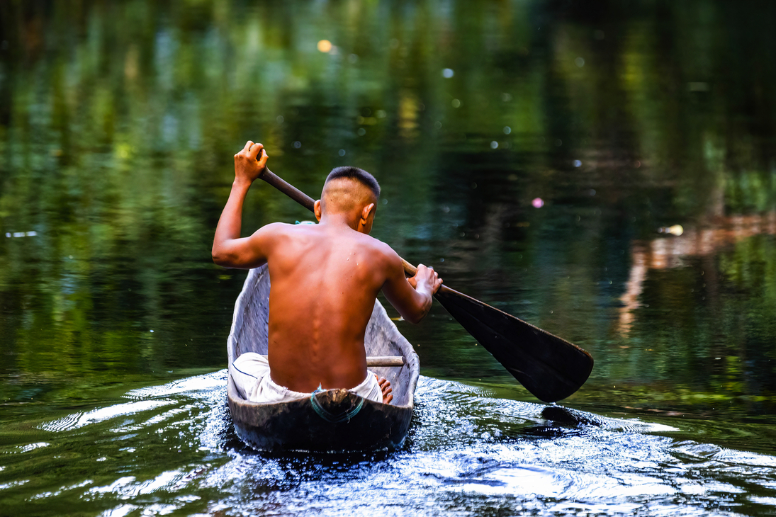 einheimischer Stammesangehöriger im Amazonas-Regenwald in einem handgefertigten Boot - © PhotoSpirit - stock.adobe.com